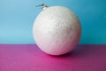 White snow small round xmas festive Christmas ball, Christmas toy plastered over sparkles on a pink purple blue background Royalty Free Stock Photo