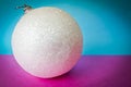 White snow small round xmas festive Christmas ball, Christmas toy plastered over sparkles on a pink purple blue background Royalty Free Stock Photo