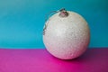 White snow small round xmas festive Christmas ball, Christmas toy plastered over sparkles on a pink purple blue background Royalty Free Stock Photo