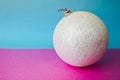 White snow small round xmas festive Christmas ball, Christmas toy plastered over sparkles on a pink purple blue background Royalty Free Stock Photo