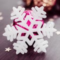 White snowflake on background of magenta and gold xmas baubles. Royalty Free Stock Photo