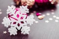 White snowflake on background of magenta and gold xmas baubles. Royalty Free Stock Photo