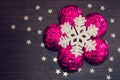 White snowflake and magenta xmas baubles on brown wooden background with stars. Royalty Free Stock Photo