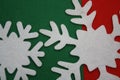 White snowflakes cut from felt on a red and green background with copy space. Christmas decoration Royalty Free Stock Photo