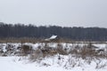 White snowy landscape with a lonely cozy house on the background of a dense dark forest Royalty Free Stock Photo