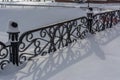 White snowy street, pathway along the park trees surrounded with a beautiful black cast iron fence, elegant wrought iron Royalty Free Stock Photo