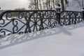 White snowy street, pathway along the park trees surrounded with a beautiful black cast iron fence, elegant wrought iron Royalty Free Stock Photo