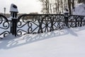 White snowy street, pathway along the park trees surrounded with a beautiful black cast iron fence, elegant wrought iron Royalty Free Stock Photo