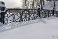 White snowy street, pathway along the park trees surrounded with a beautiful black cast iron fence, elegant wrought iron Royalty Free Stock Photo