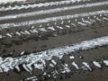 White snowy tires imprints on black asphalt road