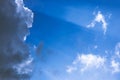 White soft clouds slowly being covered by one big dark cloud from left side while rays of light are coming out from Royalty Free Stock Photo