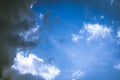 White soft clouds slowly being covered by one big dark cloud from left side while rays of light are coming out from Royalty Free Stock Photo