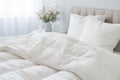 white soft duvet lying against background of bed and bedside table with vase of flowers,close-up,concept of preparing for winter Royalty Free Stock Photo