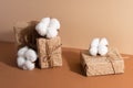 The white soft flowers cotton decorate paper gift boxes on beige background. Holiday concept. Idea for presents