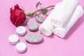 White soft towels, red rose, stones and candles for skin care and spa on a pink background Royalty Free Stock Photo