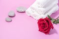 White soft towels, red rose and stones for skin care and spa on a pink background Royalty Free Stock Photo
