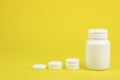 White soluble tablets near the bottle on a yellow background. The medicine. Copy space