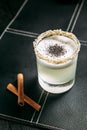 White sour muddy alcohol cocktail wit a foam and sesame seeds in a glass