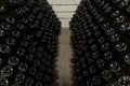 White sparkling wine bottles in the cellars of winery, sparkling wine fermenting on stands