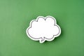 The White speech bubble shaped post it note on green background with copy space