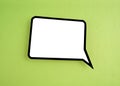 The White speech bubble shaped post it note on green background with copy space