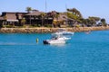 A white speed boat sailing in the deep blue waters of the Dana Point Harbor with lush green trees and brown buildings on the shore Royalty Free Stock Photo