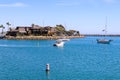 A white speed boat sailing in the deep blue waters of the Dana Point Harbor with lush green trees and brown buildings on the shore Royalty Free Stock Photo