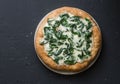 White spinach mozzarella pizza on a dark background