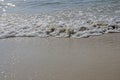 White sponges of waves on sand beach