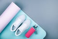 White sport shoes sneakers blue pink yoga mat,glass water bottle on grey background. Royalty Free Stock Photo