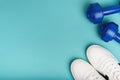 White sport sneakers shoes and blue dumbbells on the blue background. Royalty Free Stock Photo