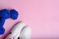 White sport sneakers shoes and blue dumbbells on the pink background. Royalty Free Stock Photo