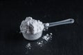 White sports nutrition powder. Soluble creatine in a measuring spoon to increase athlete`s stamina and strength. On a stone gray