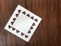 White square blank paper which was punched in heart shape on dark brown wood table Royalty Free Stock Photo