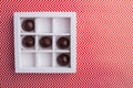 White square box with round chocolate candies.