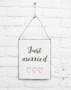 White square metal plate on white bricks background - with text just married for love couples and weddings