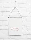 White square metal plate with cute red hearts and space for own text on white brick background Royalty Free Stock Photo