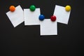 White square note stickers are attached with colored magnets on a black Board. Royalty Free Stock Photo