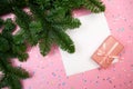 White square paper card, christmas tree branch border, gift box with ribbon and holographic glitter stars confetti on