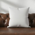 White square pillow with subtle grid pattern sits on a brown, tufted leather sofa. Sofa