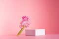 White square podium for display cosmetic and goods with fresh spring flowers standing on gentle pastel pink background.