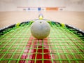 White squash ball on the strings of a racket in the middle of a