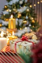 A white star gift with a red ribbon and candle lights under the Christmas tree create a festive mood Royalty Free Stock Photo