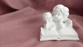 A white statuette of two angels reading a book Royalty Free Stock Photo