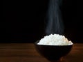 White steam rice in black ceramic bowl with smoke on black