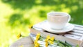 White steaming cup of hot coffee owith yellow flowers and green nature blurred Royalty Free Stock Photo