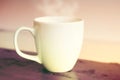 White steamy cup on red wooden table