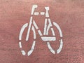 White Stencil Bicycle Lane Symbol on Red Asphalt Pavement Royalty Free Stock Photo