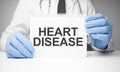 White sticker with text Heart Disease in doctor& x27;s hands with a stethoscope Royalty Free Stock Photo