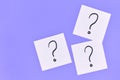 White sticky notes with handwritten question mark symbol on purple background
